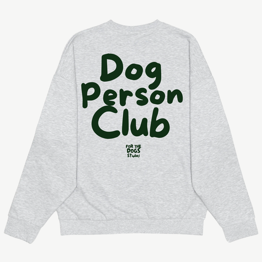 Back of a light grey crewneck with large dark green Dog Person Club lettering and the For The Dogs Studios logo.