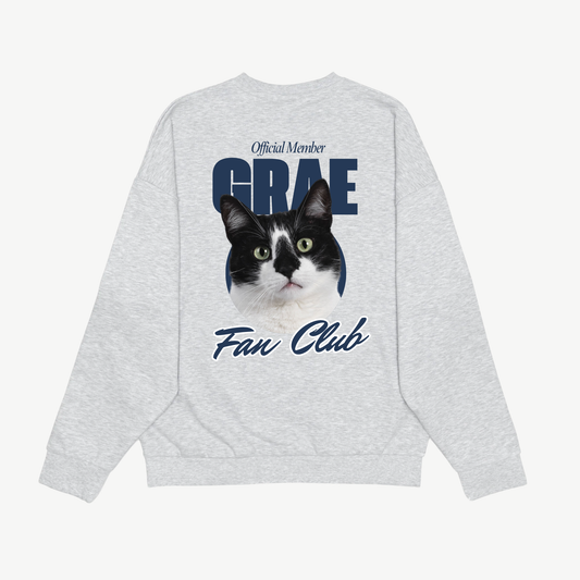 Back of a light grey Fan Club crewneck with a black-and-white cat portrait and navy lettering.