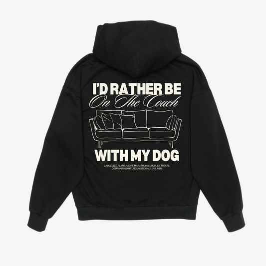 Back of a black hoodie with a cream couch illustration and “I’d rather be on the couch with my dog” lettering.