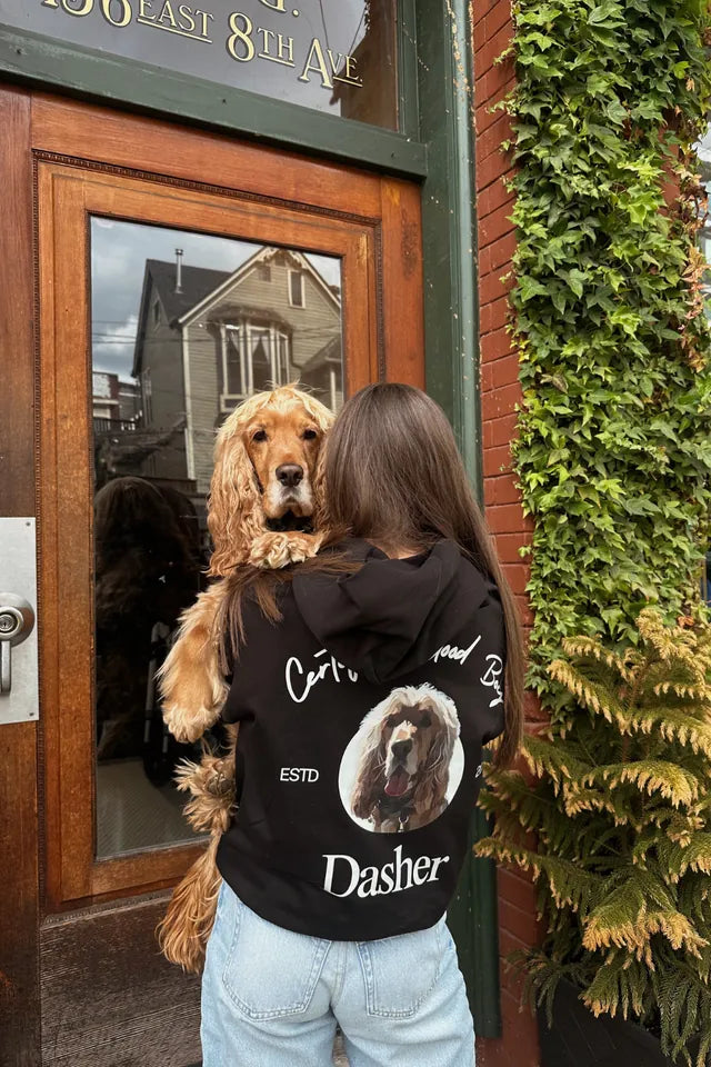 A dog person wearing a custom Dasher hoodie and holding their dog